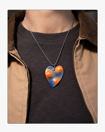 A model wearing the TOPO Heart necklace in Photon; a sculptural ceramic pendant with blue and orange airbrush gradient.