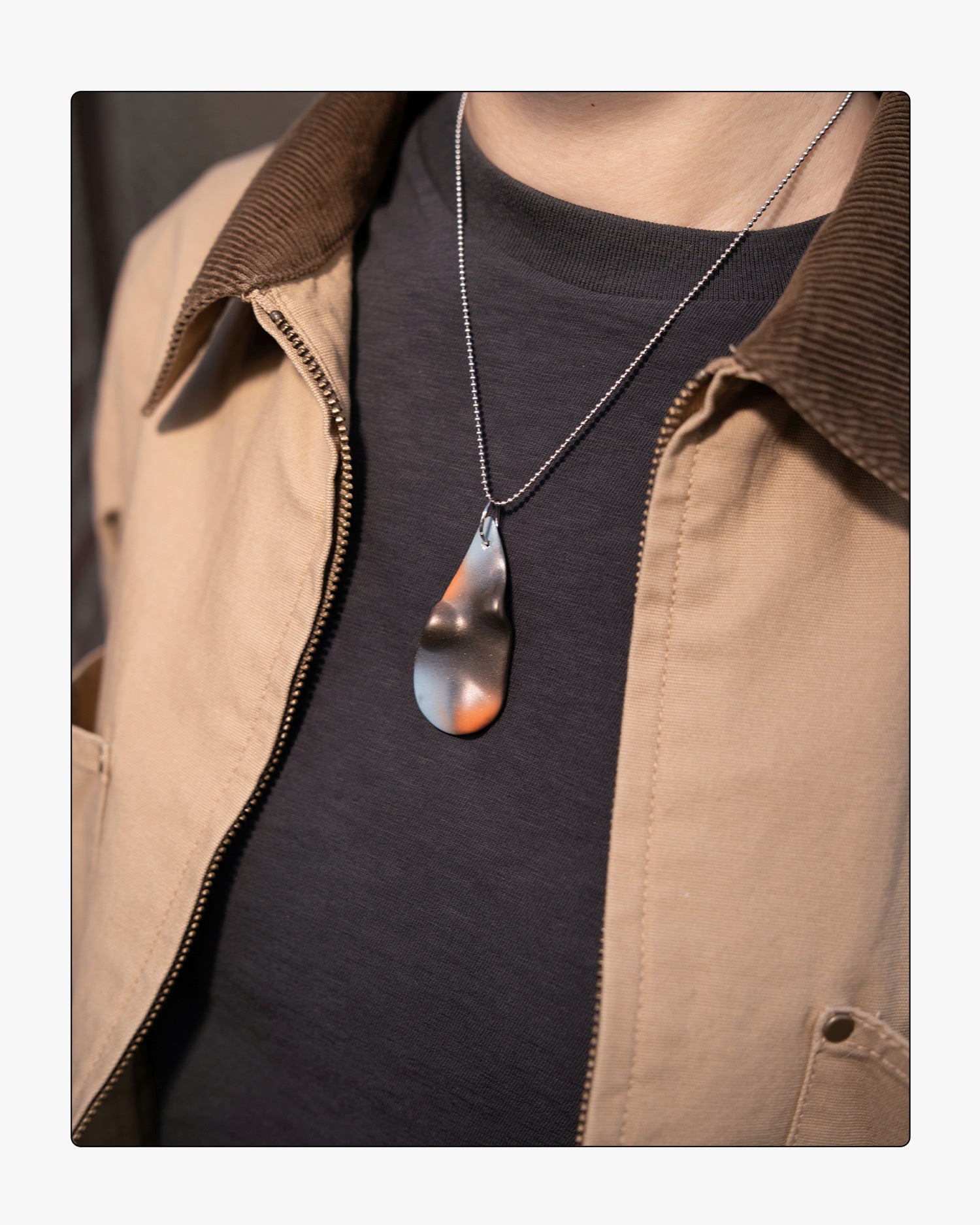 Minimalist umber ceramic teardrop necklace worn on 18 inch silver chain, set against a neutral background