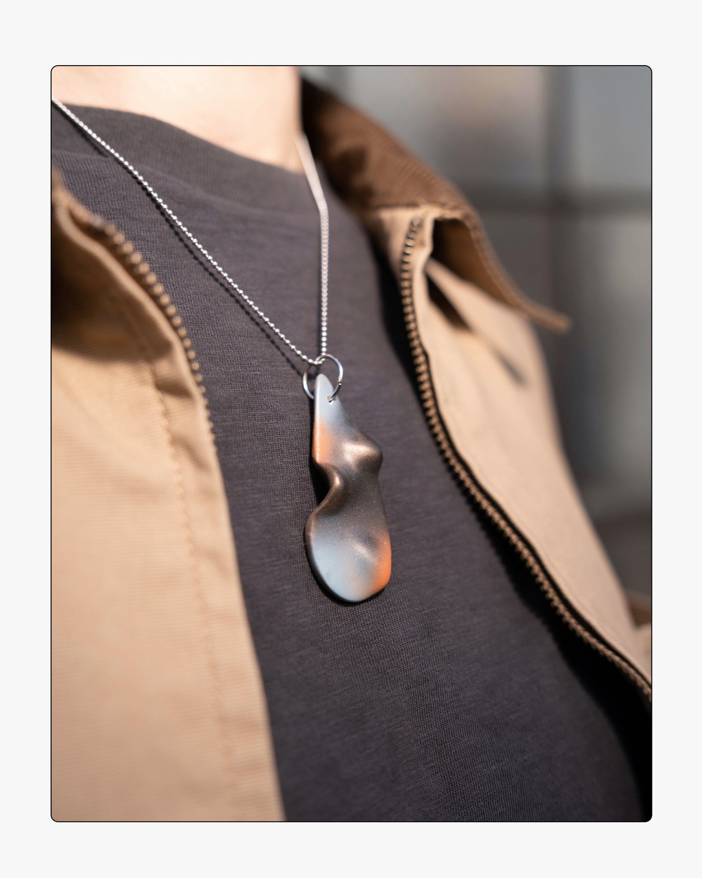 Minimalist umber ceramic teardrop necklace worn on 18 inch silver chain, set against a neutral background