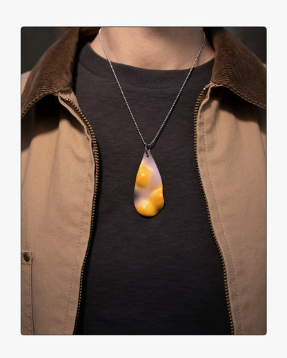 A person wearing the TOPO Teardrop in Eclipse, showcasing the contrast of solar yellow and black against a dark garment and tan jacket.