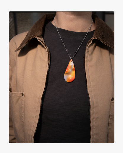Minimalist Frequency ceramic necklace worn on an 18-inch silver ball chain, showcasing the tactile relief and soft purple and orange tones against a neutral background